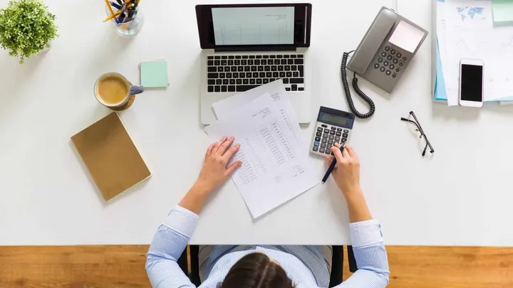 Profesional trabajando con software de gestión, documentos y calculadora